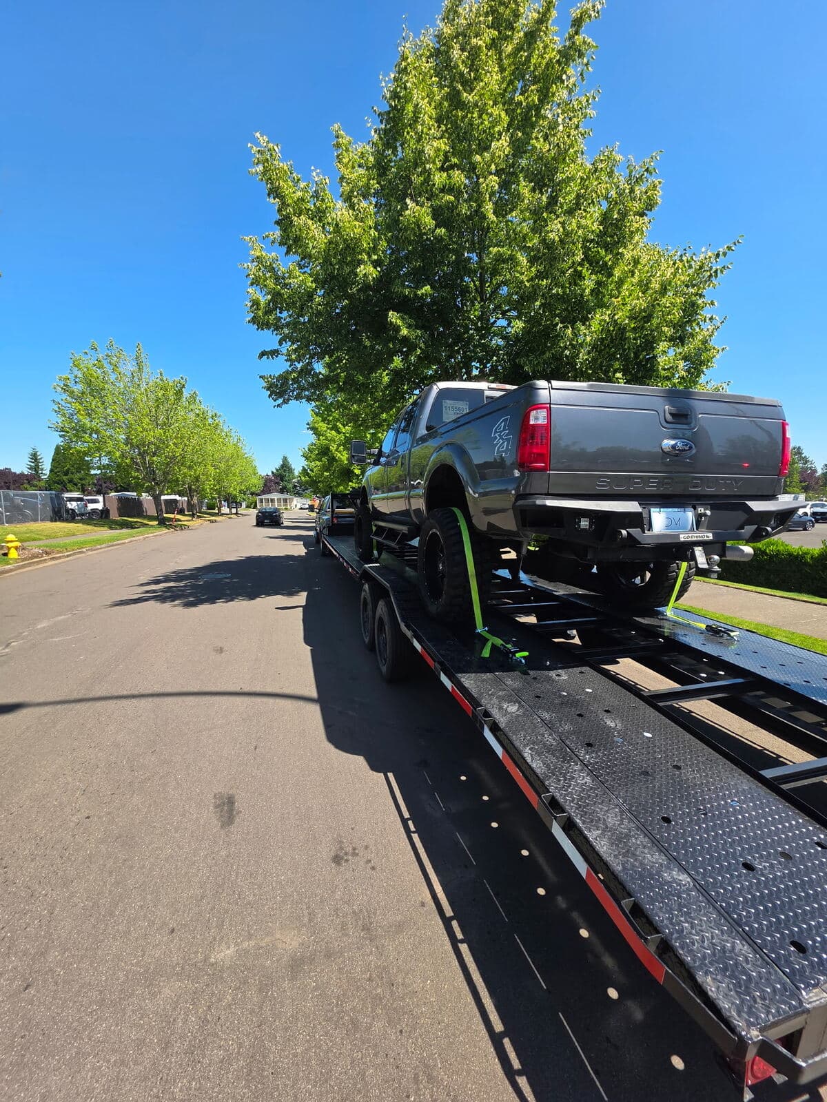 Gray Ford Super Duty 4x4 secured on Stellar Transport's two-vehicle trailer
