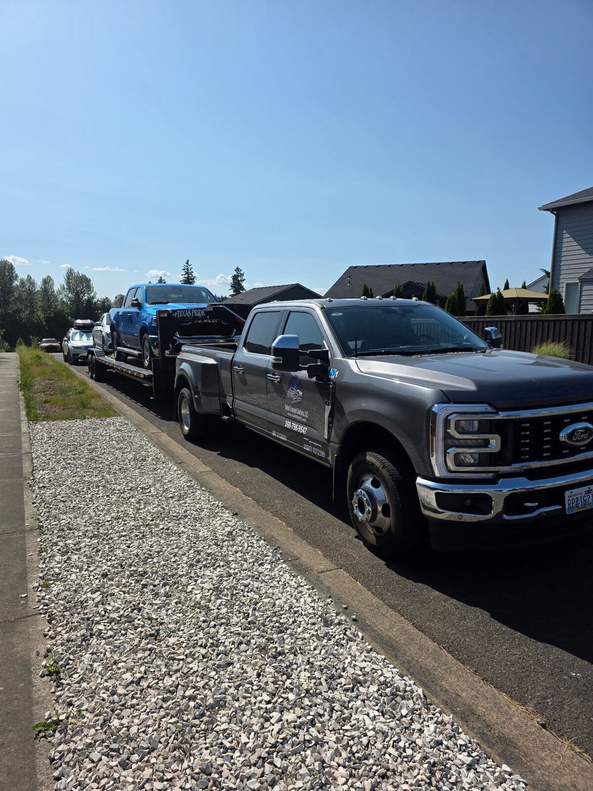 Stellar Transport's branded Ford F-350 dually hauling two pickups on its two-vehicle trailer
